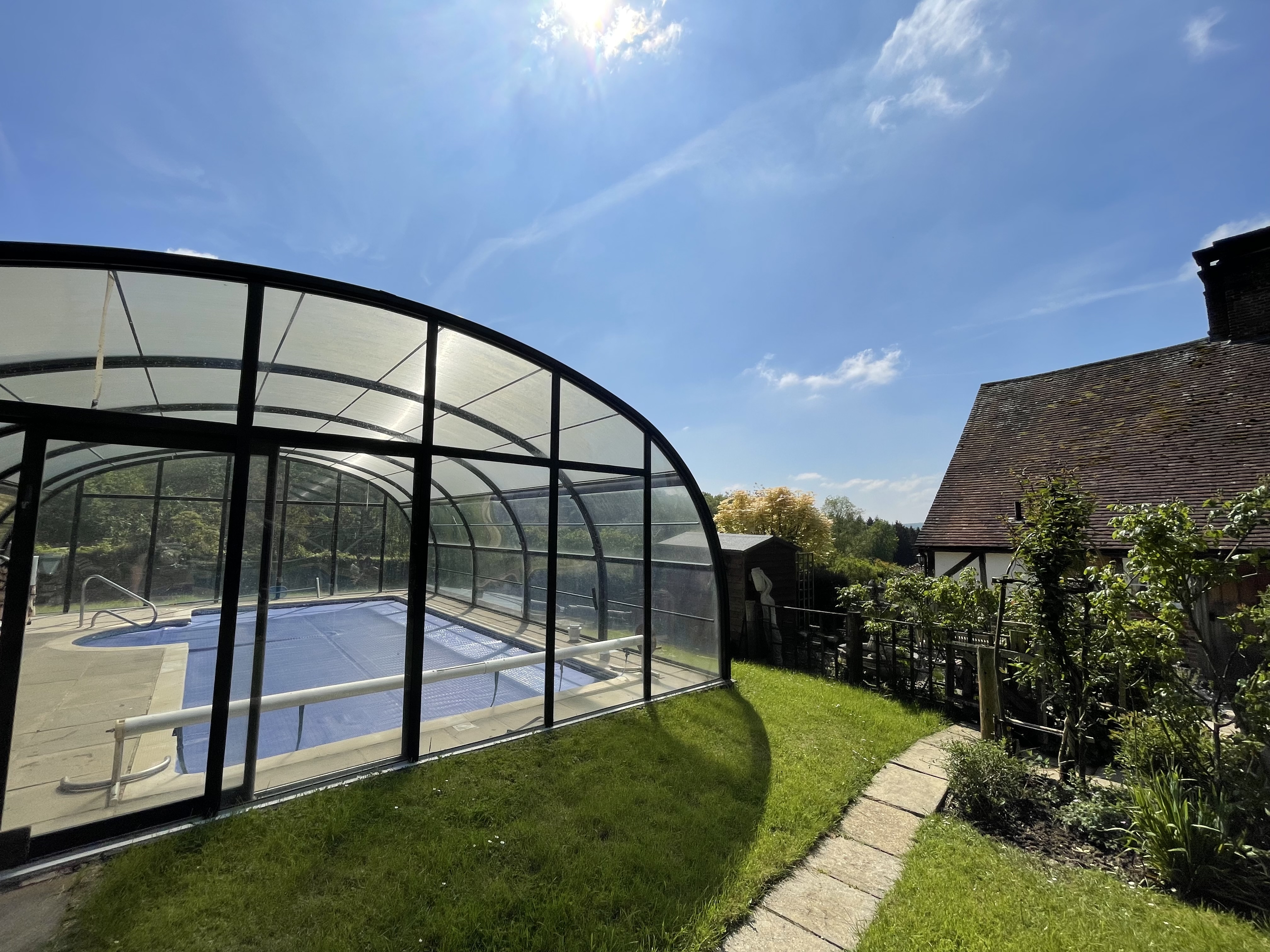 The enclosed swimming pool with the farmhouse visible behind